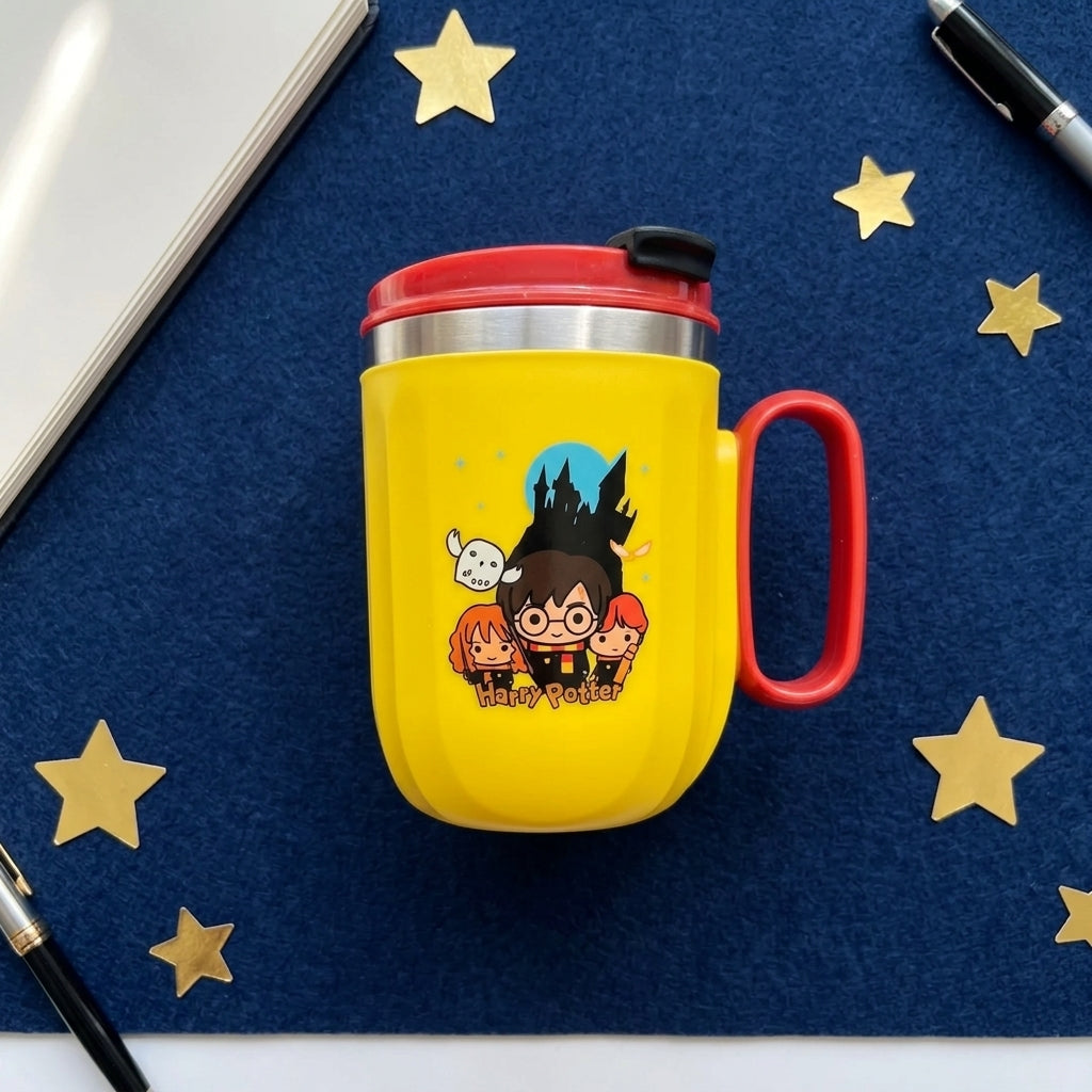 Yellow mug with red handle and lid on a blue surface with star decorations